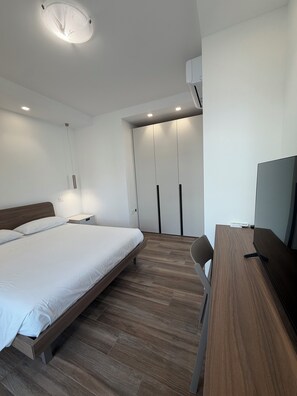 A modern bedroom with a bed, bedside table, and a TV. - Le Calendule Luxury Apartment (Olbia)