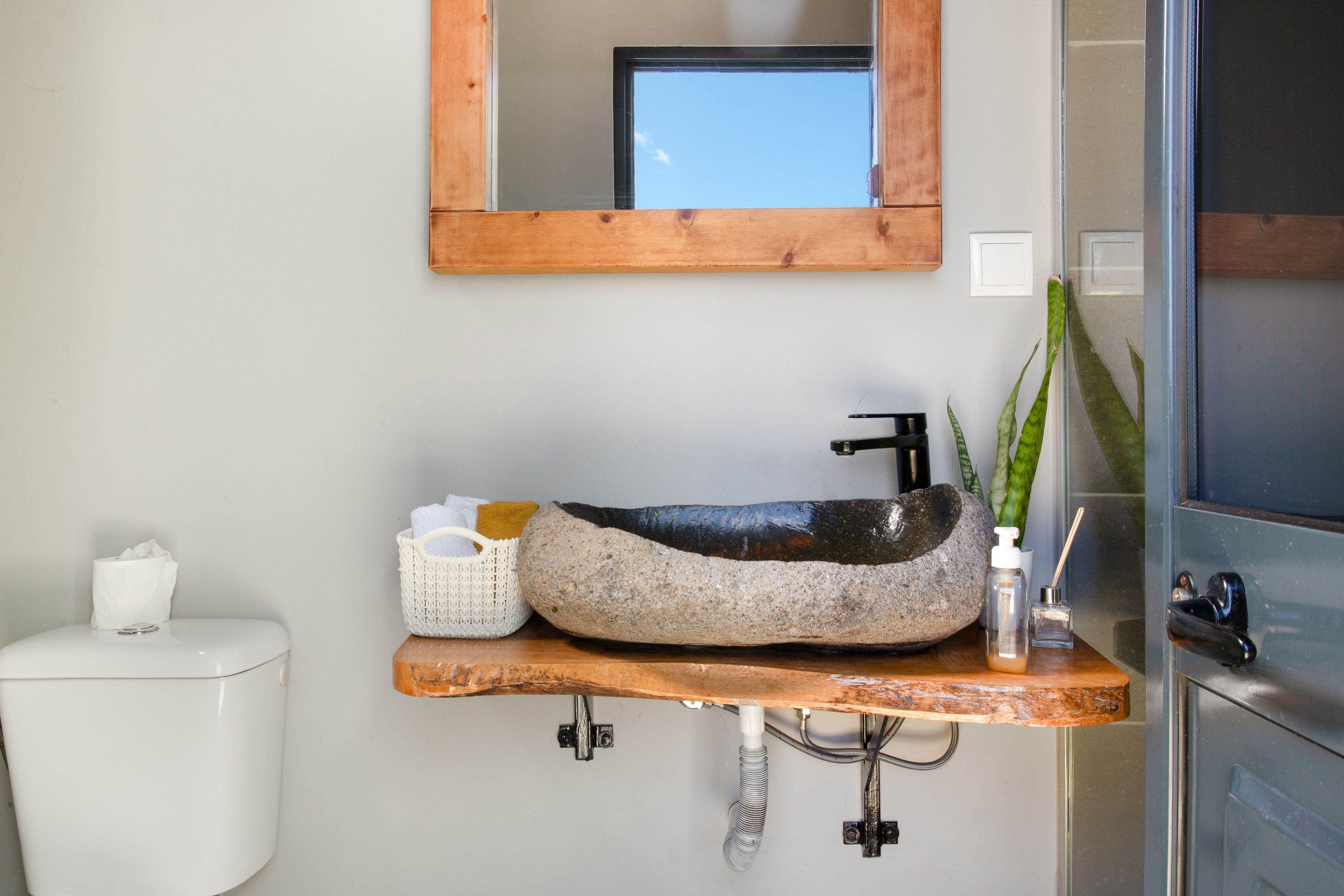 Een badkamer met een wastafel van steen, een spiegel, toilet en een douchegedeelte.