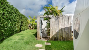 A pathway leading to a wooden gate with a metal gate, surrounded by a well-maintained lawn and a hedge.