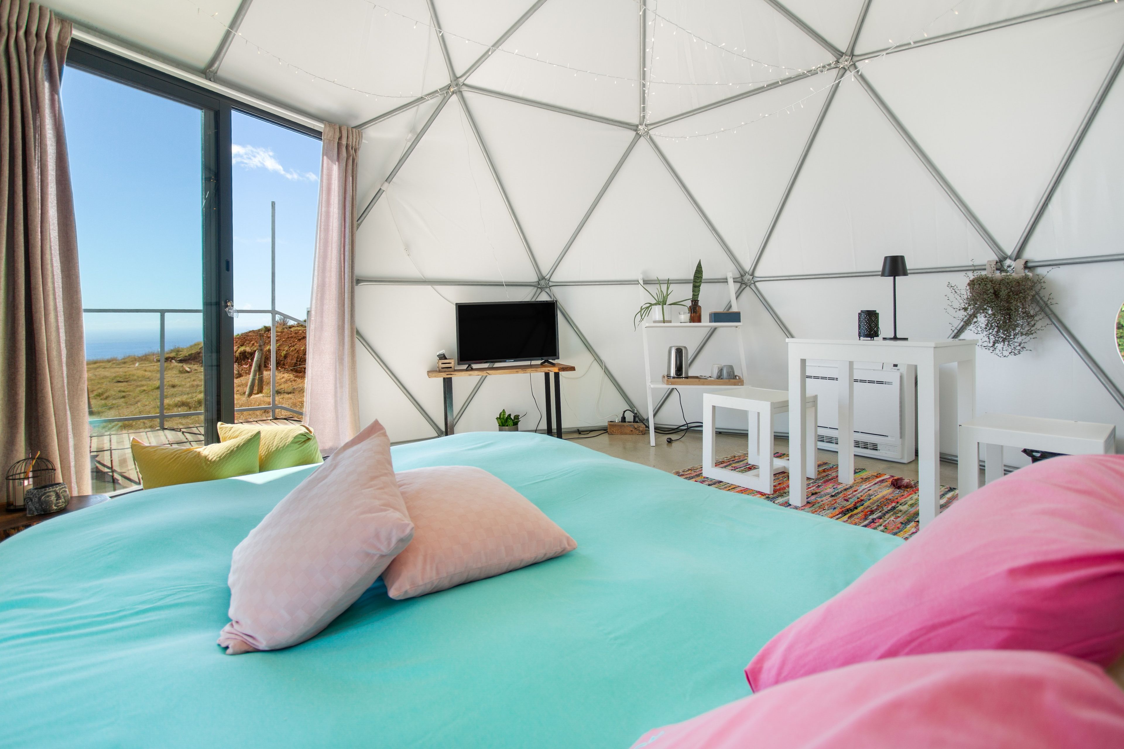 A modern bedroom with a large bed, a television, and a view of the outdoors.