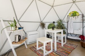 A tent-style room with white furniture, a colorful rug, and various plants.