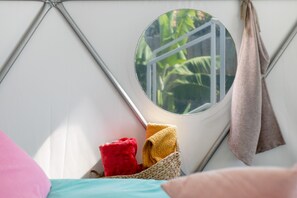 Un interior acogedor con un ventanal redondo, una cesta tejida y una cama con almohadas.