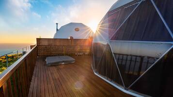 Una terraza de madera con vista al océano y una estructura abovedada grande.