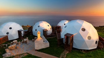 Geodesic dome accommodations with a view of the sea at sunset.