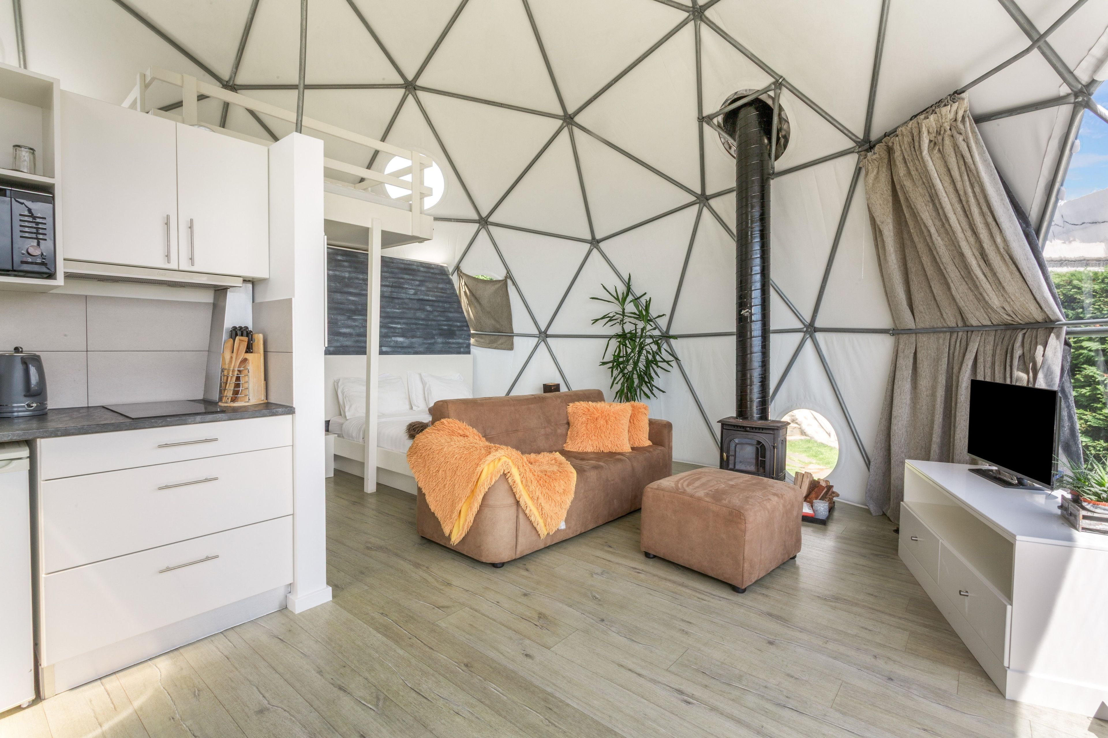 Een modern interieur met een geometrisch plafond, een zithoek, een televisie en een keukenhoek.