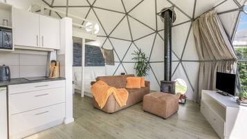 Een modern interieur met een geometrisch plafond, een zithoek, een televisie en een keukenhoek.