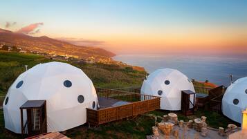 Alojamiento en cúpula geodésica con terraza de madera y vistas a la costa.