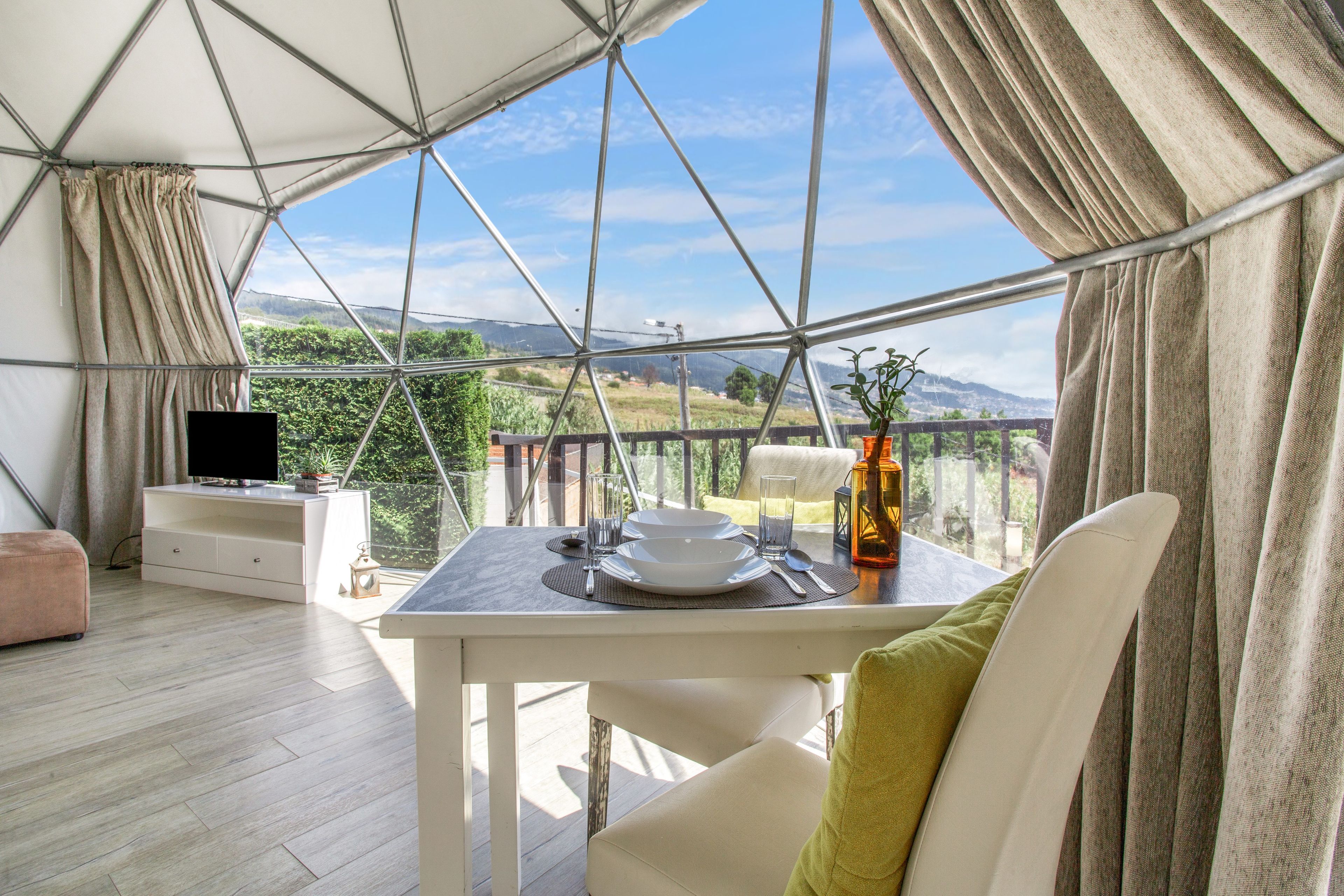 Comedor con una mesa lista para dos, televisor y vistas al exterior.
