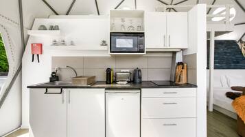 Eine kompakte Küche mit Mikrowelle, Toaster und Kaffeemaschine.
