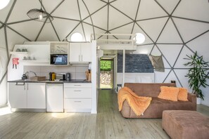 A modern interior with a kitchen, dining area, and living space featuring geometric ceiling design and natural light.