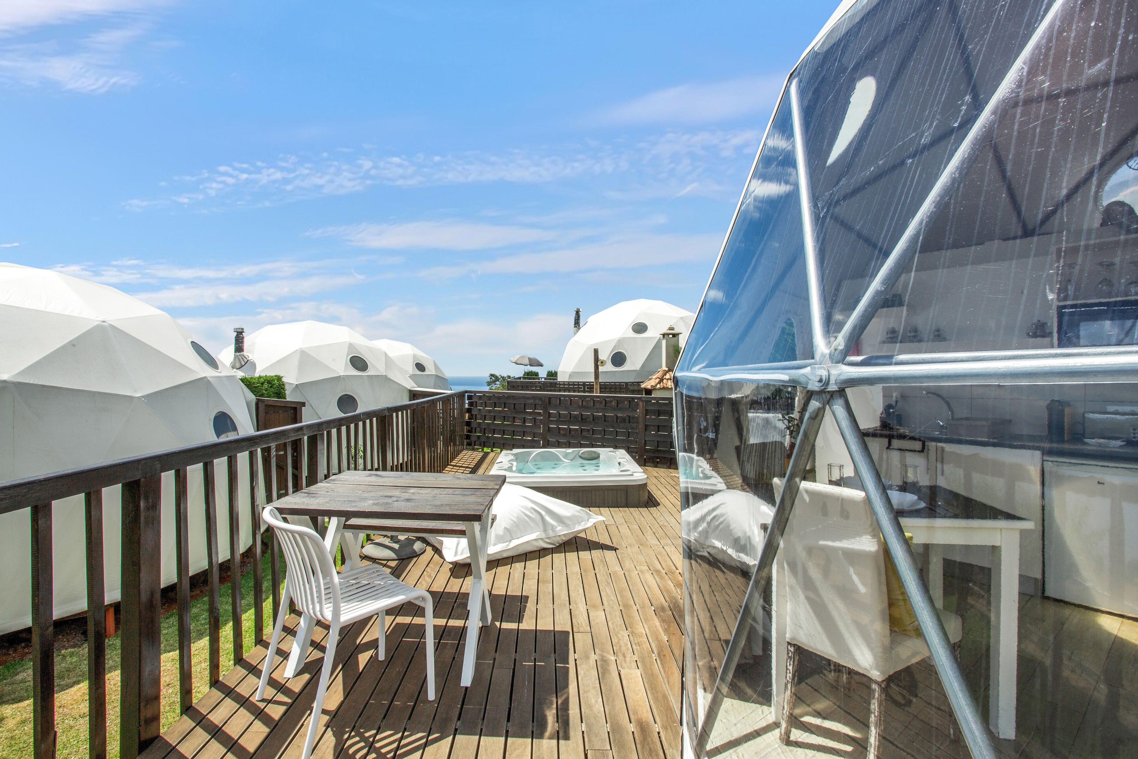 Eine Terrasse mit Tisch und Stühlen, umgeben von kuppelförmigen weißen Bauwerken.