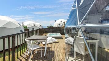 Eine Terrasse mit Tisch und Stühlen, umgeben von kuppelförmigen weißen Bauwerken.