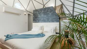 Un dormitorio moderno con cama, almohadas, una toalla azul y un ventanal grande.