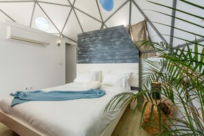 Une chambre moderne avec un lit, des oreillers, une serviette bleue et une grande fenêtre.