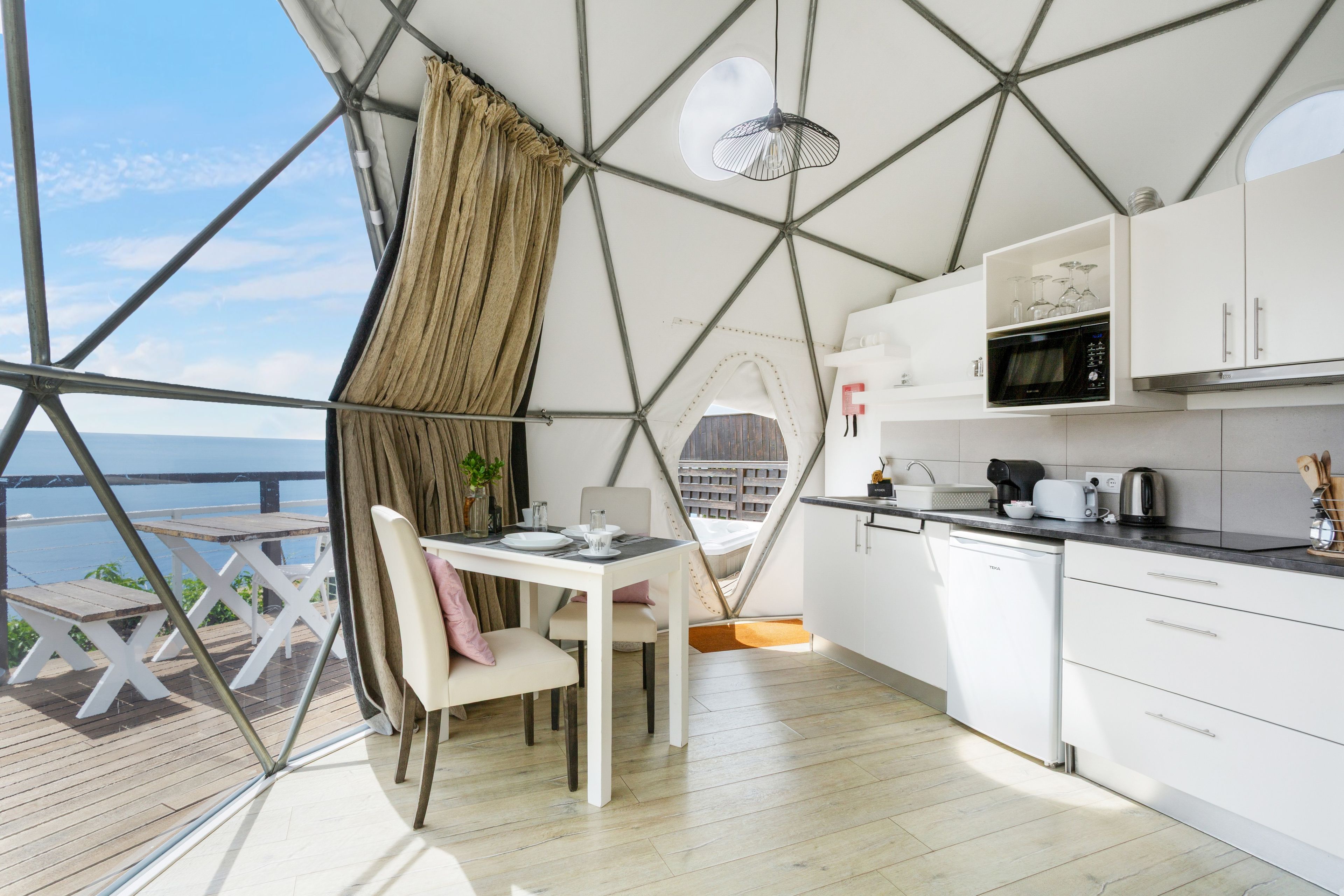 Een moderne keuken met witte kasten, een magnetron en een eethoek met een tafel en stoelen.