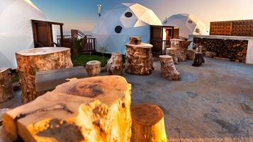 Varias estructuras de cúpulas geodésicas con terraza de madera y pared de piedra.