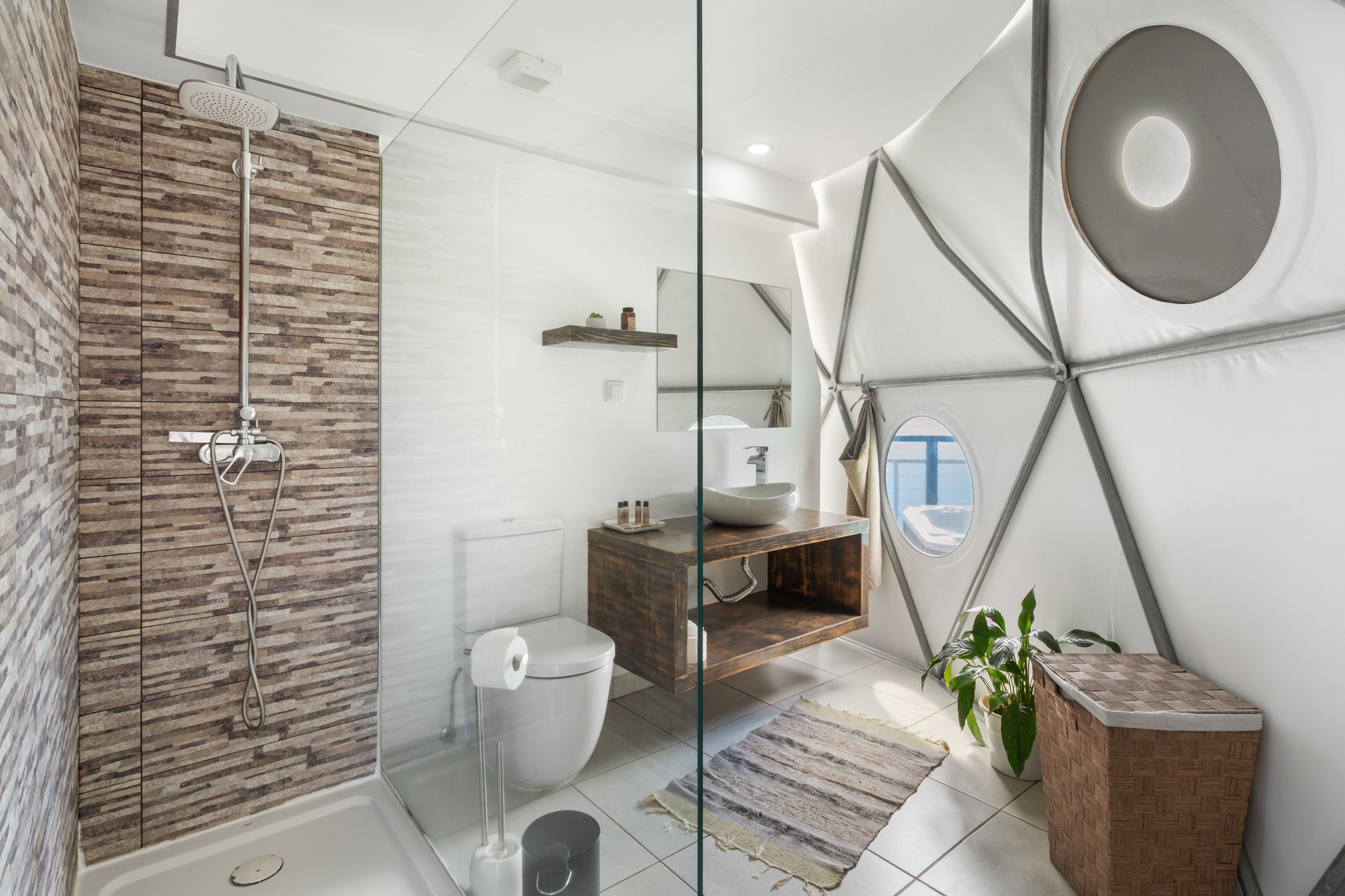 A modern bathroom with a shower, toilet, sink, and a large mirror.