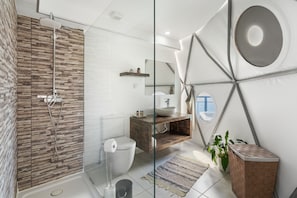 A modern bathroom with a shower, toilet, sink, and a large mirror.