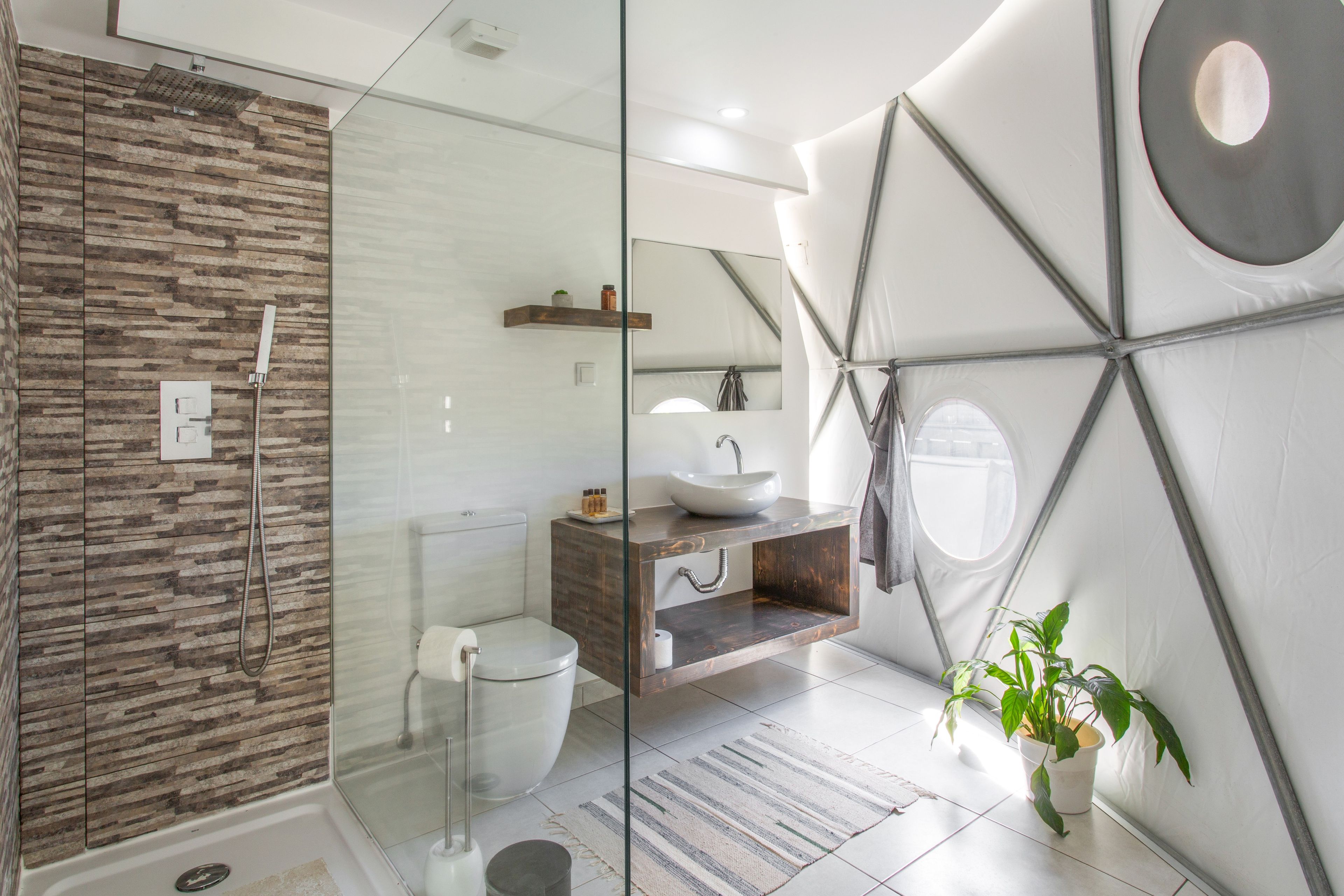 Une salle de bain moderne avec une douche à parois de verre, des toilettes, un lavabo avec un vasque et un miroir.