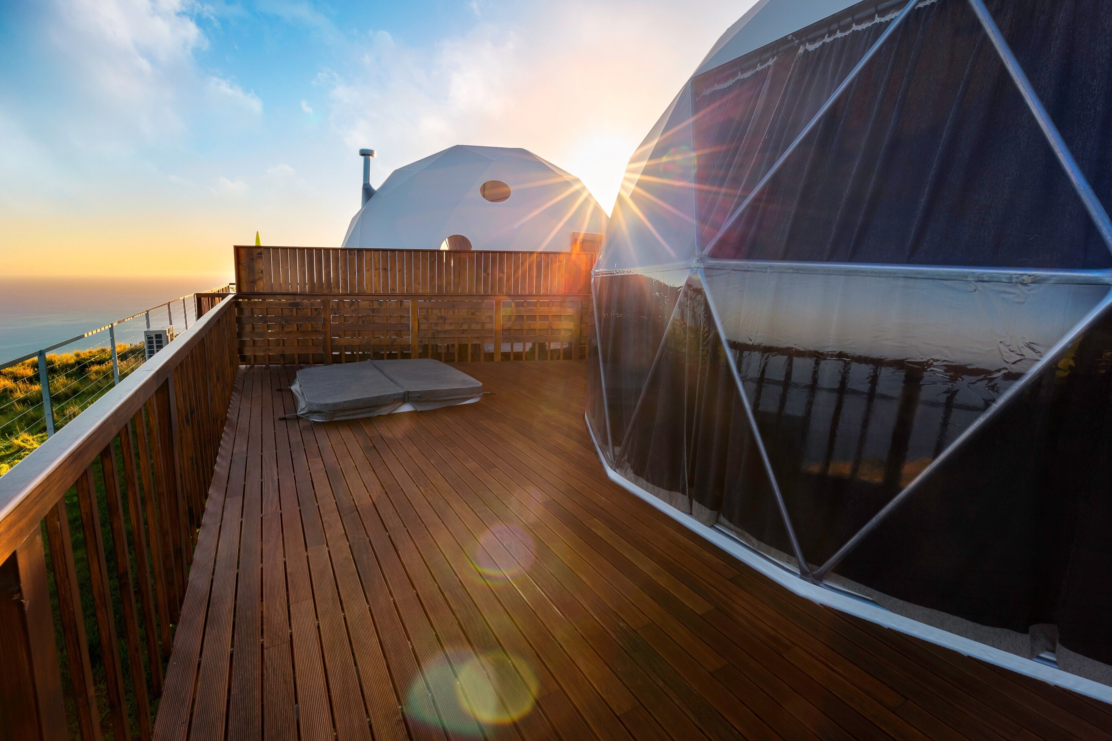 A wooden deck with a view of the ocean and a large dome structure.
