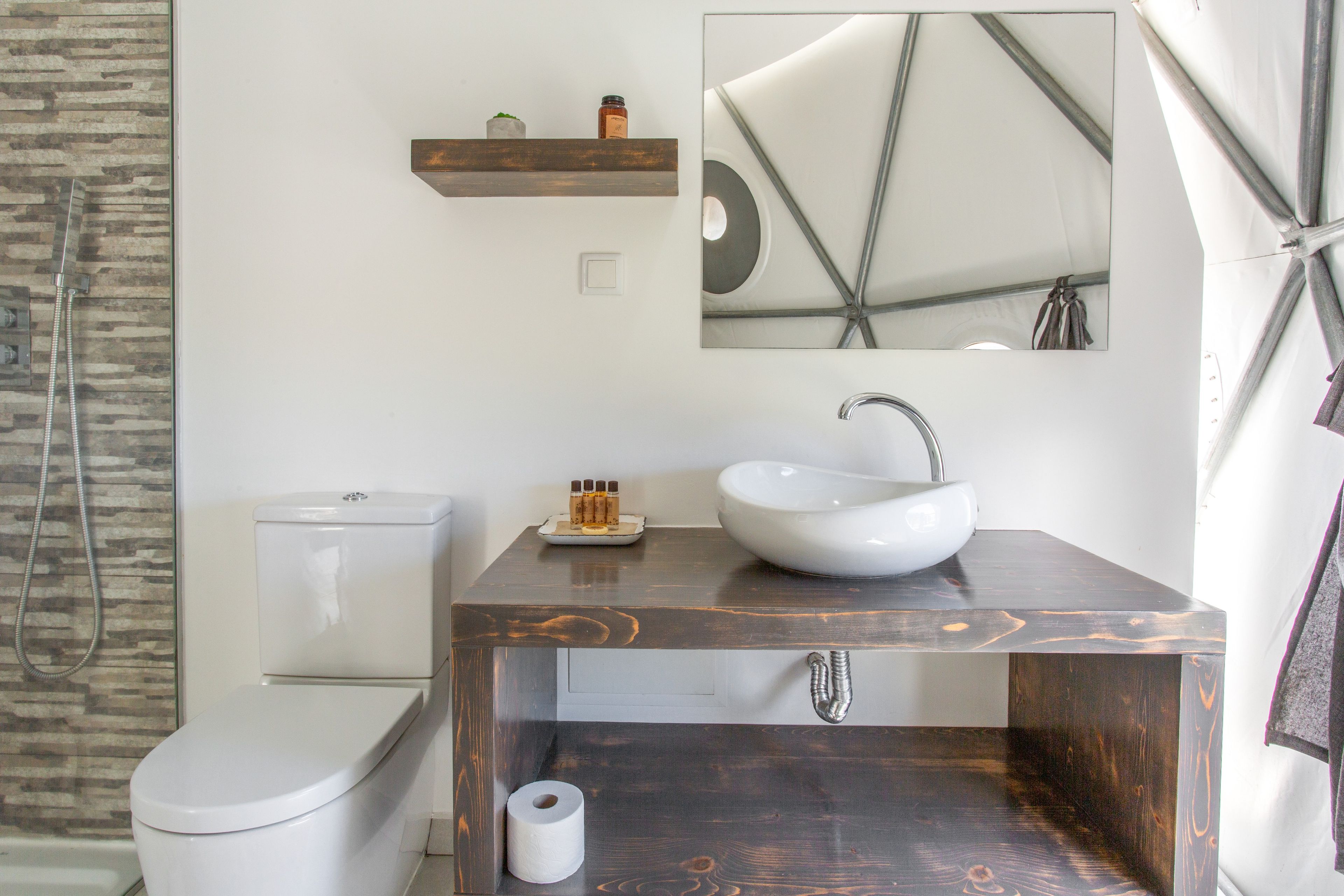 A bathroom with a white toilet, a wooden vanity with a white sink, and a mirror above the vanity.
