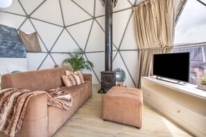 Ein gemütliches Wohnzimmer mit einer Couch, einem Hocker und einem Fernseher auf einem weißen Schrank.