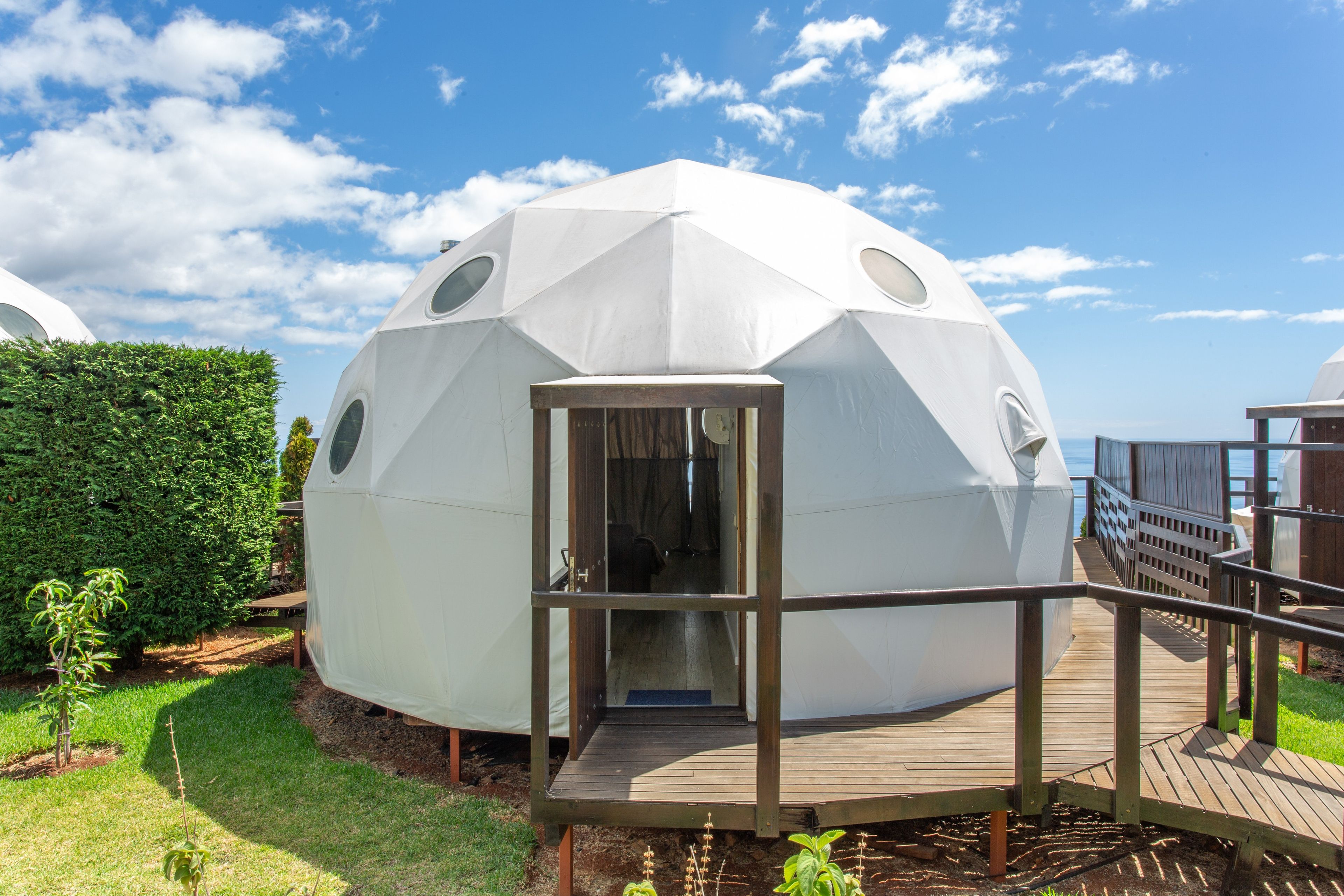 Una estructura de domo geodésico con una terraza de madera y una puerta que da al interior.