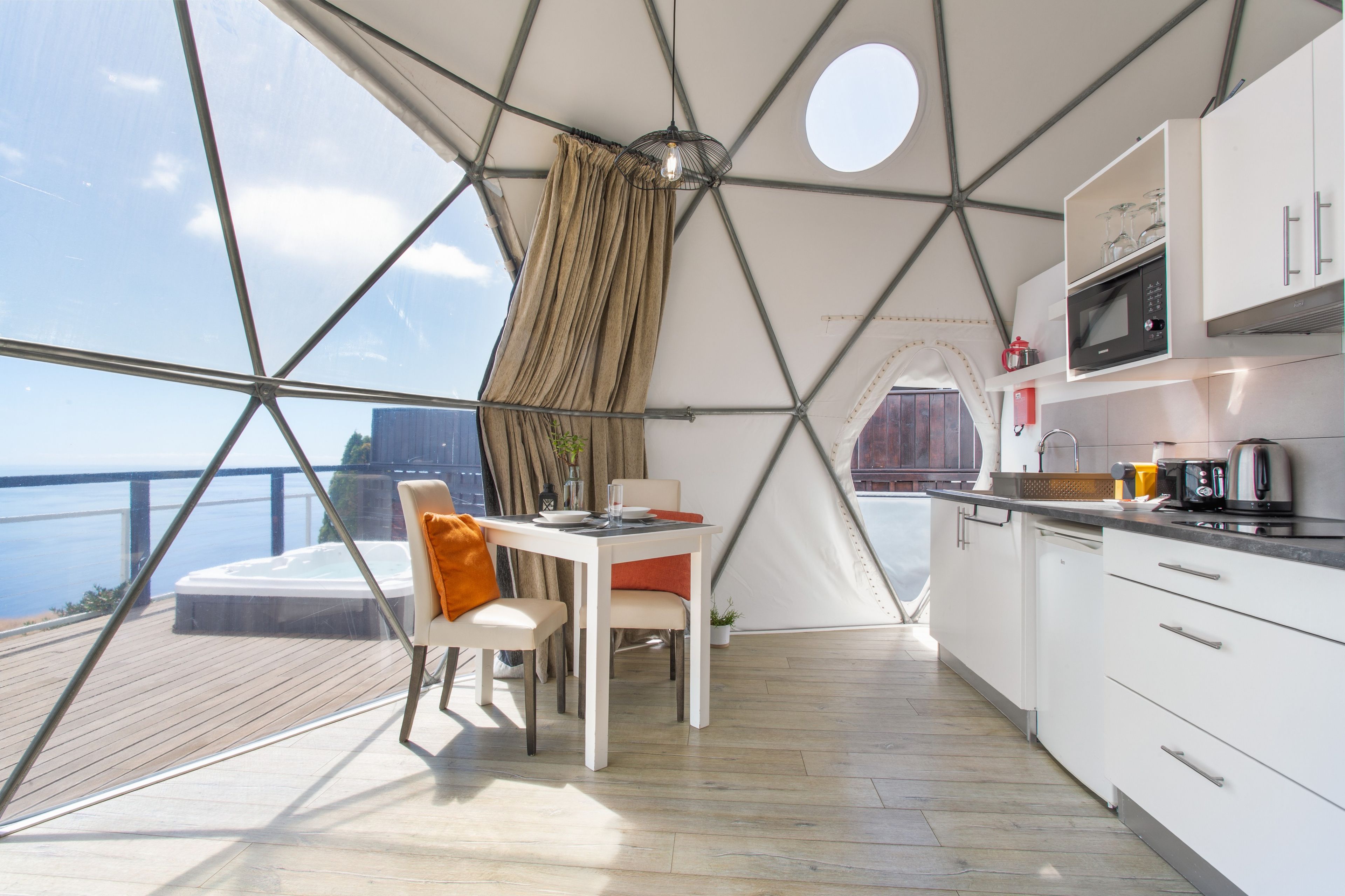 A modern kitchen with a view of the sea, a dining area with a table and chairs, and a cozy seating area with a view.