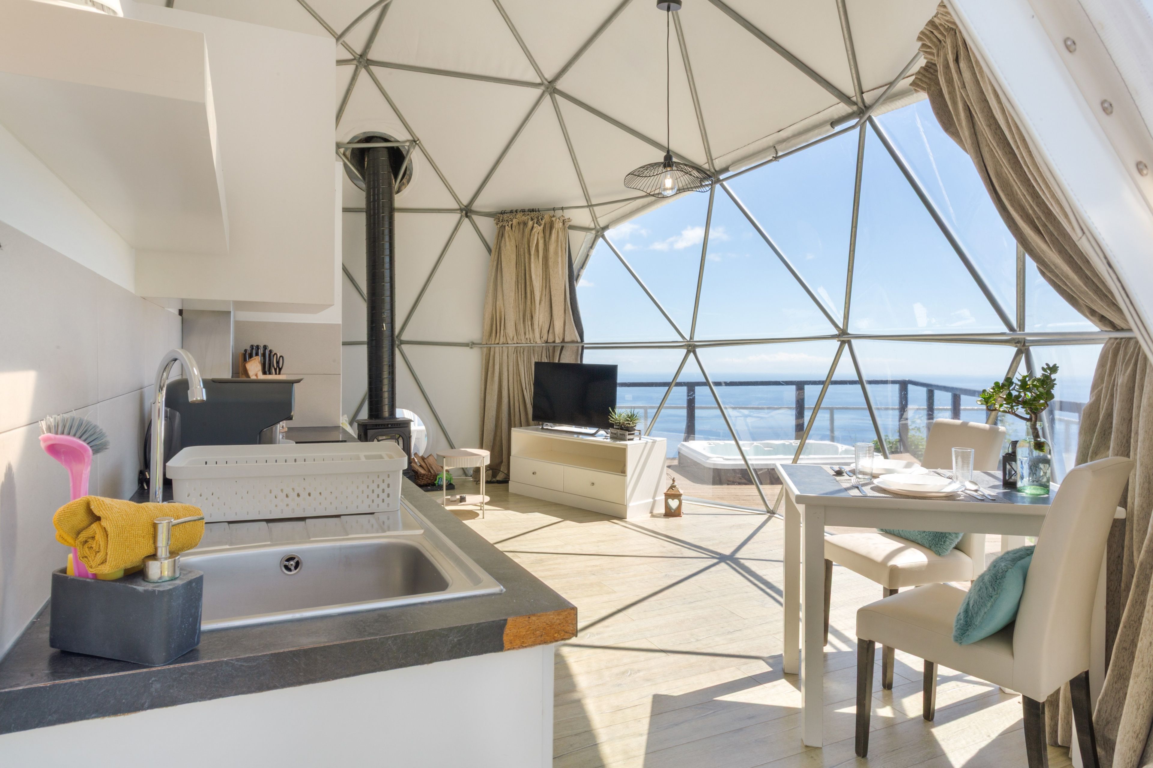 Een modern interieur met een keuken, eethoek en een groot raam met uitzicht op zee.