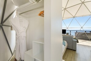 Un intérieur moderne avec un peignoir blanc suspendu, une console blanche et un coin salon offrant une vue sur la mer.
