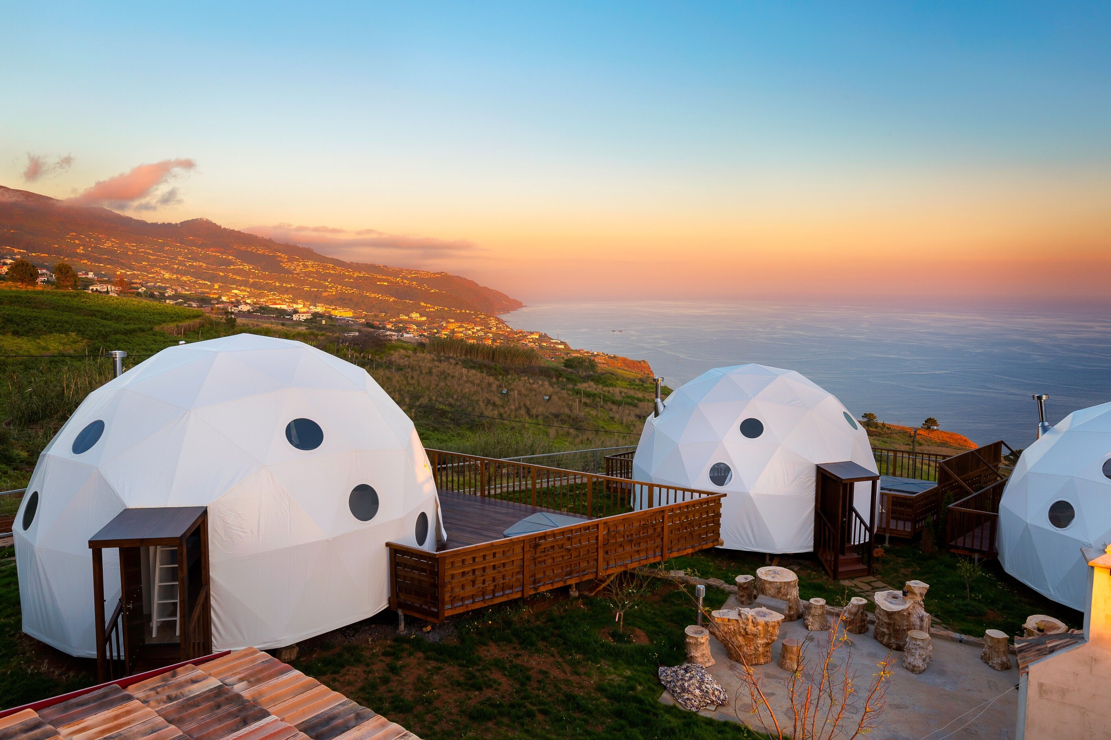 Alojamiento en cúpula geodésica con terraza de madera y vistas a la costa.