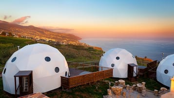 Alojamiento en cúpula geodésica con terraza de madera y vistas a la costa.