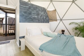 A modern bedroom with a bed, pillows, a nightstand, and a wall-mounted lamp. - Soul Glamping – Luxus, Natur, Ozeanblick & privater Jacuzzi auf Madeira (Prazeres)