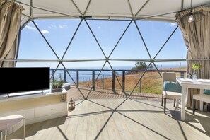 A room with a large window, a flat-screen TV, a dining table, and a chair.