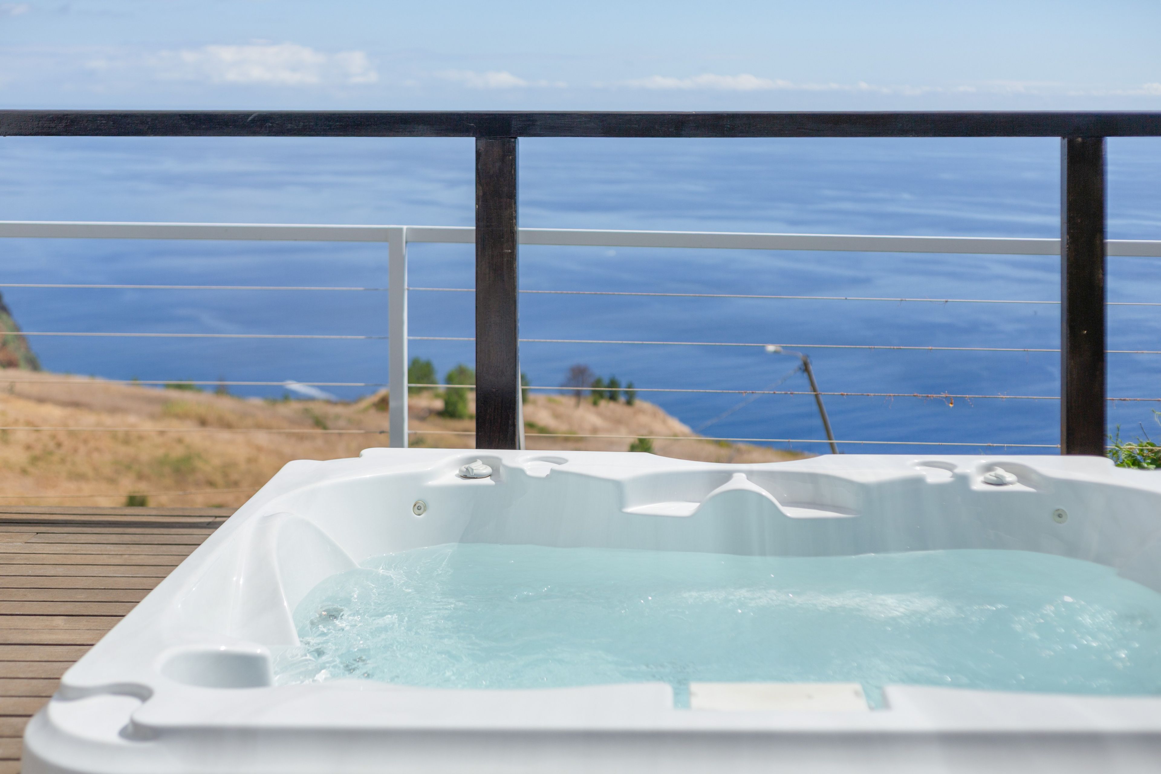 Un jacuzzi en una terraza de madera con vista al océano.