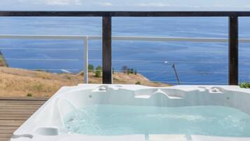 Un jacuzzi en una terraza de madera con vista al océano.