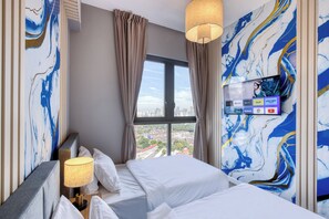 Quarto de hotel com uma cama grande, televisão fixada na parede e janela com vista para a cidade.