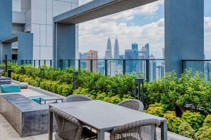 Terraço no telhado com área de estar ao ar livre, vista do horizonte da cidade e estrutura de um edifício moderno.