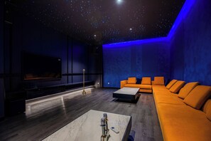 Uma sala de cinema moderna com uma grande televisão de tela plana, um sofá e uma mesa de centro.