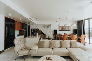 A modern living room with a sofa, a coffee table, and a dining area with chairs.