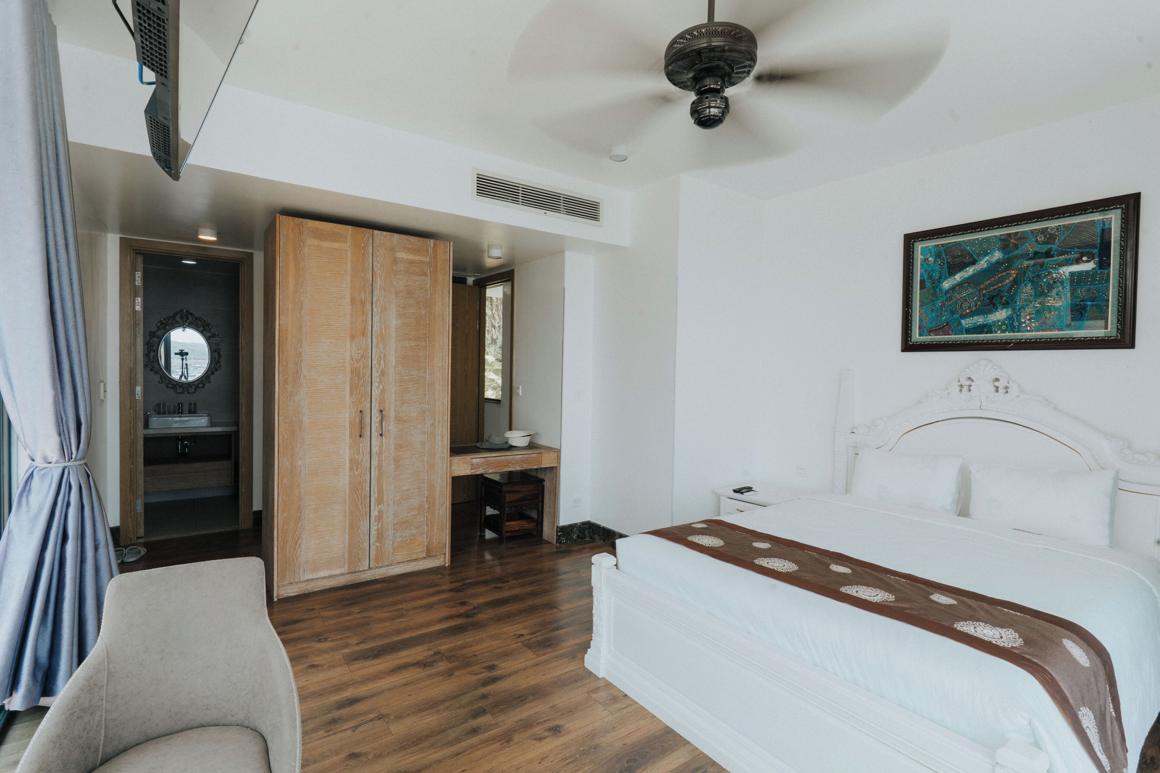 Een hotelkamer met een bed, een bureau, een kledingkast en een plafondventilator.