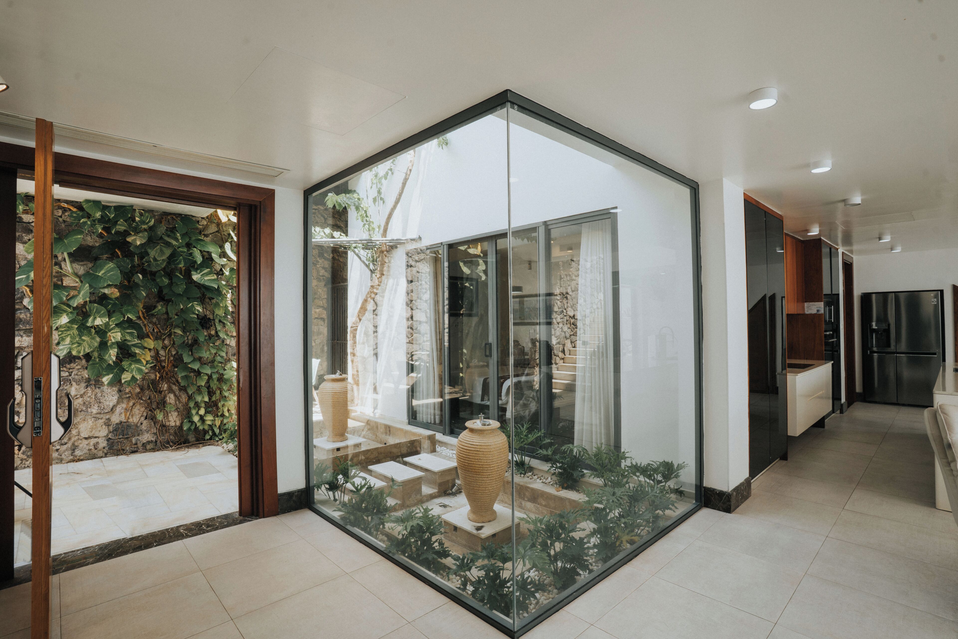 A modern kitchen with a built-in refrigerator and a glass partition.