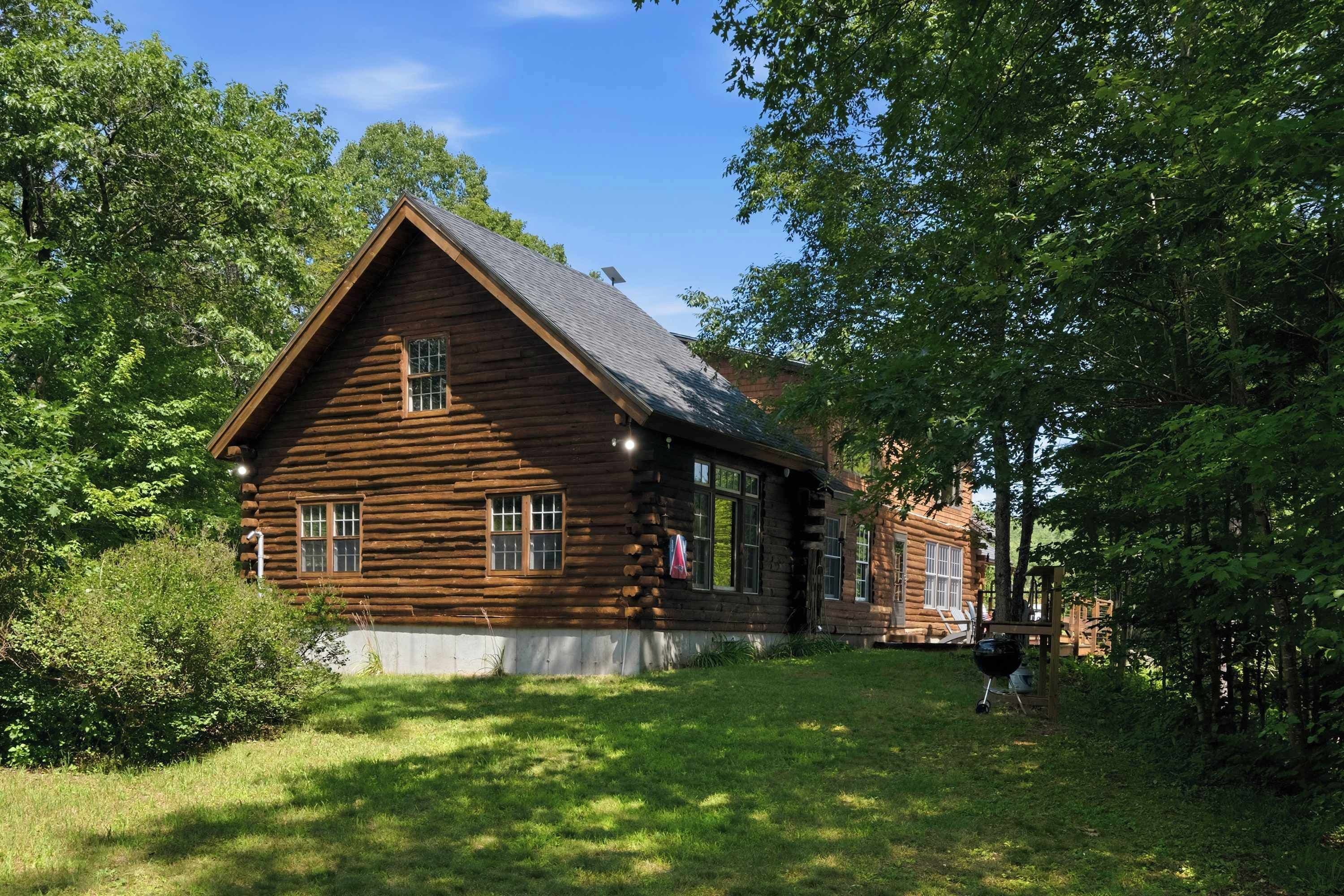 Eine Blockhütte mit einem steilen Satteldach, einer Veranda und einer kleinen Holzterrasse.
