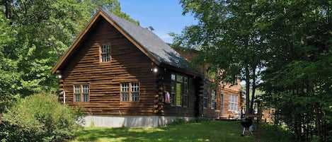 Eine Blockhütte mit einem steilen Satteldach, einer Veranda und einer kleinen Holzterrasse.