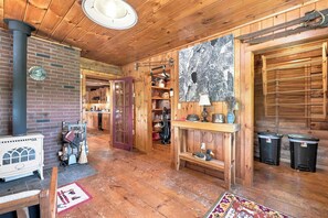 Interior d'una cabana rústica amb paret de maó, terres de fusta, zona de cuina i una finestra gran amb vistes.