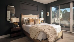 A bedroom with a large bed, bedside tables, a mirror, and a view through a glass door.