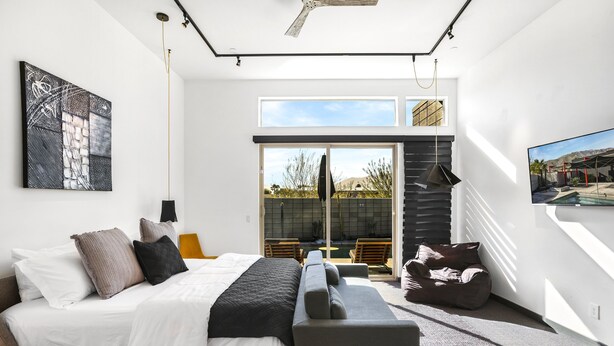 Un dormitorio moderno con cama, un banco y vistas a una zona de piscina al aire libre.