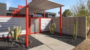 Un edificio moderno con una decoración roja y blanca, que incluye un patio cubierto con cactus y un camino de hormigón.