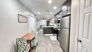 Una cocina moderna con comedor, que incluye una mesa y sillas de madera, un refrigerador y un ventilador de techo.