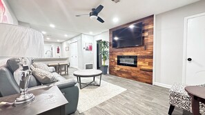 Una sala moderna con un sofá, una mesa de centro y un televisor montado en una pared de madera.